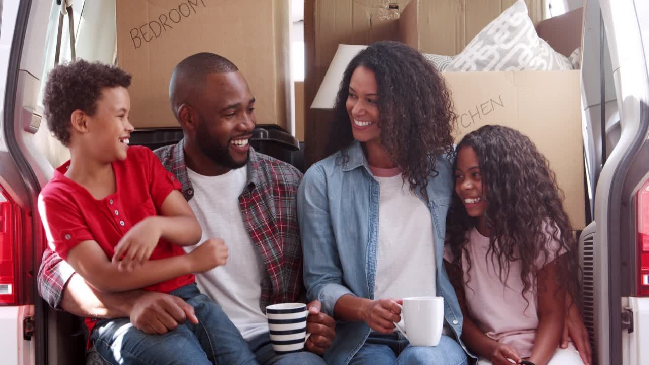 A family of 4 sitting in the back of their house-moving van